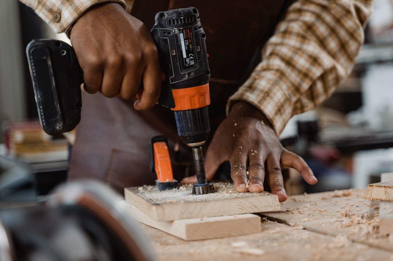 Home A craftsman skillfully uses a drill on a wooden board, showcasing woodworking precision.