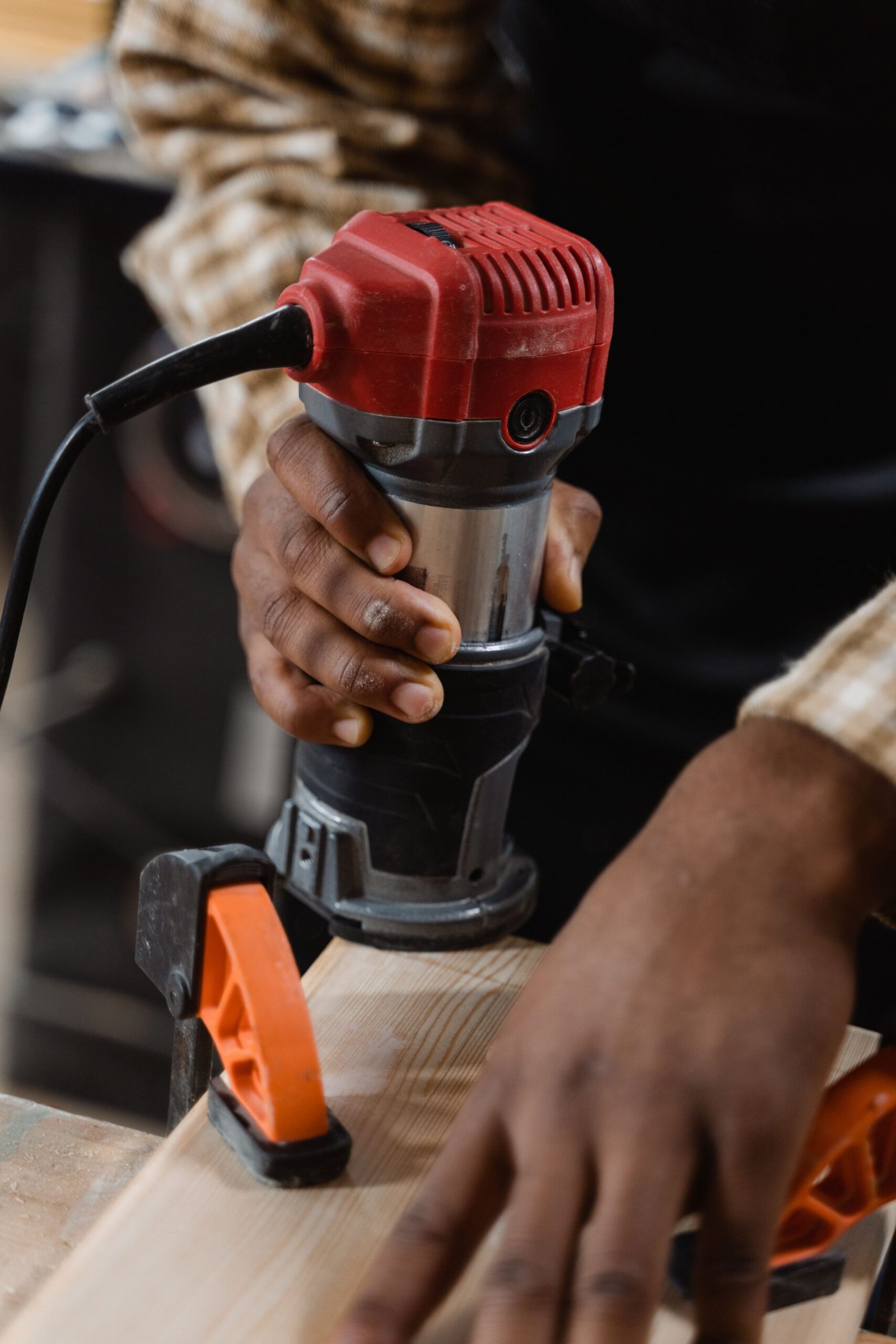Close-up of a craftsman using a power tool in a woodworking workshop.