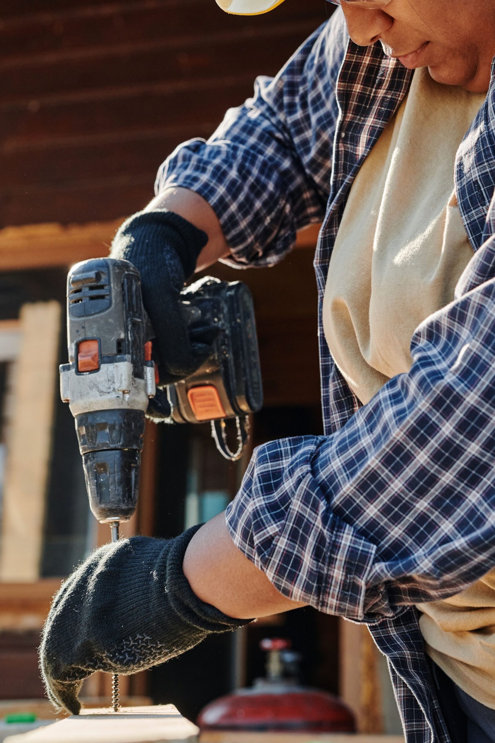 Focused shot of a carpenter using a power drill for woodworking outdoors.